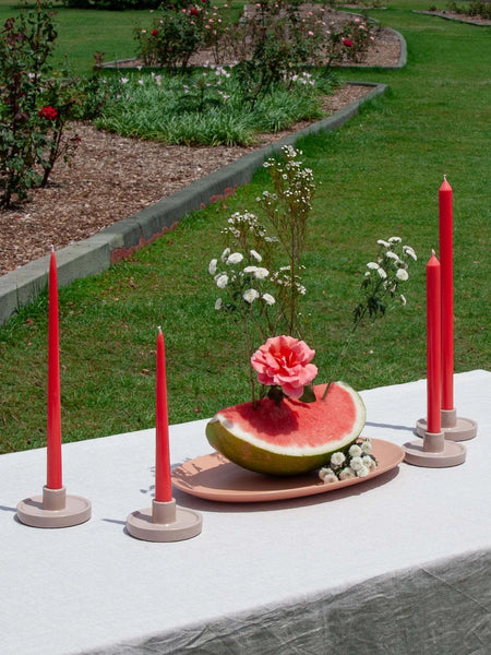 Moreton Taper Candle in Watermelon on outdoor table setting with floral arrangement.